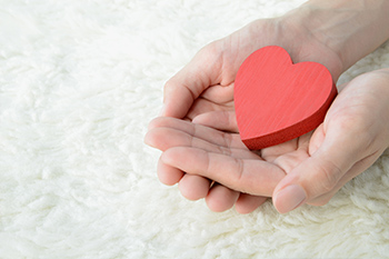 picture of hands holding red heart figurine
